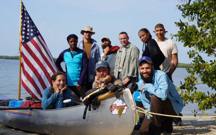 a group of veterans gathers around a canoe with an american flag 